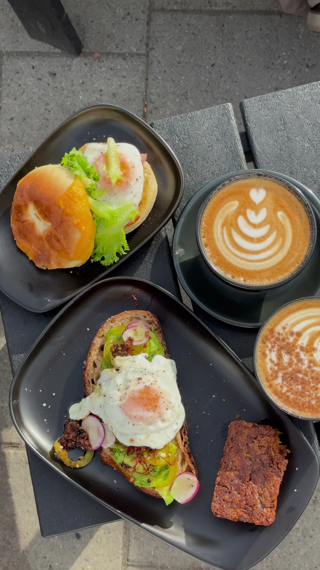 Overhead view of avocado toast, a bagel and lattes