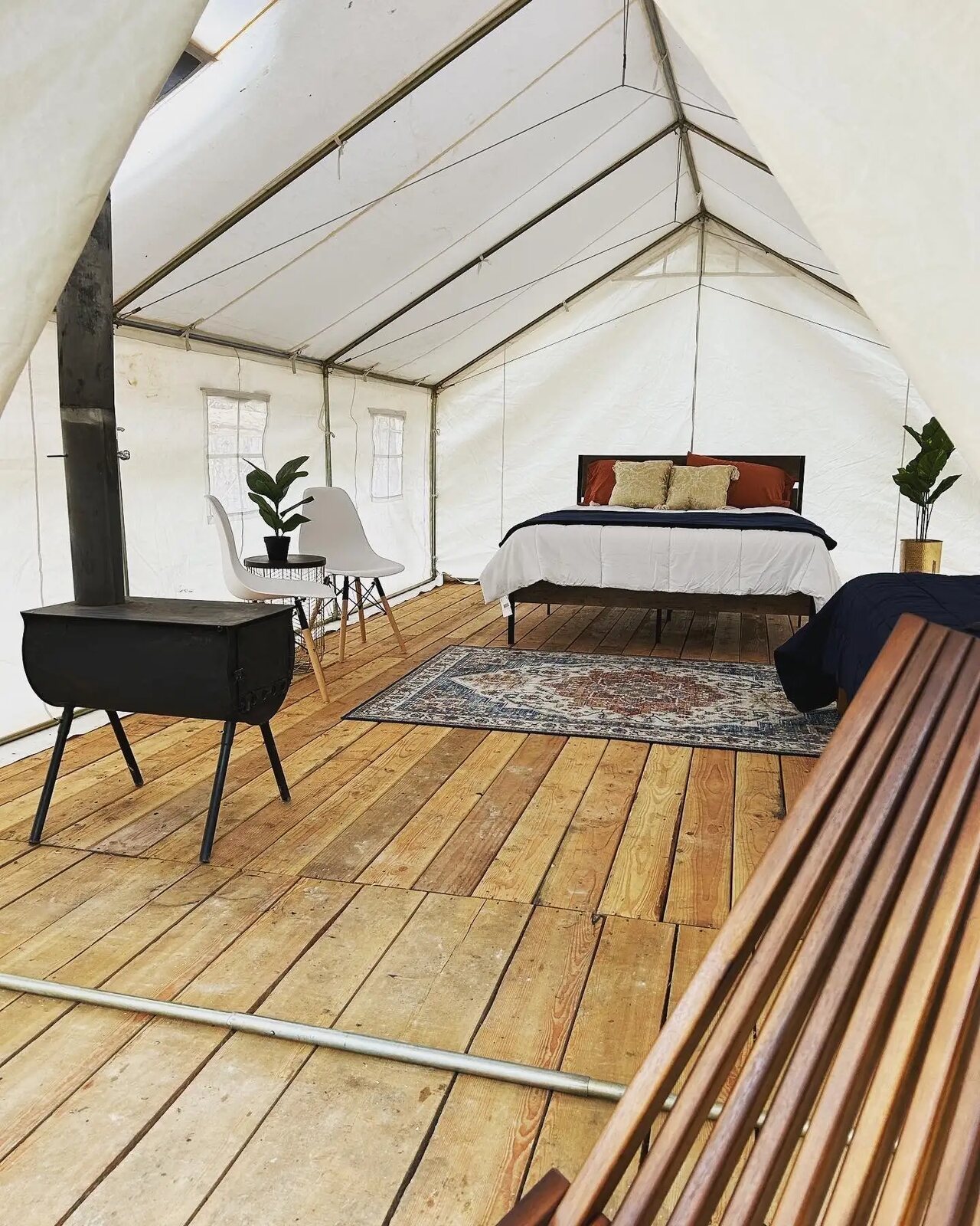 Inside the glamping tent with beds, a rug and a wood stove