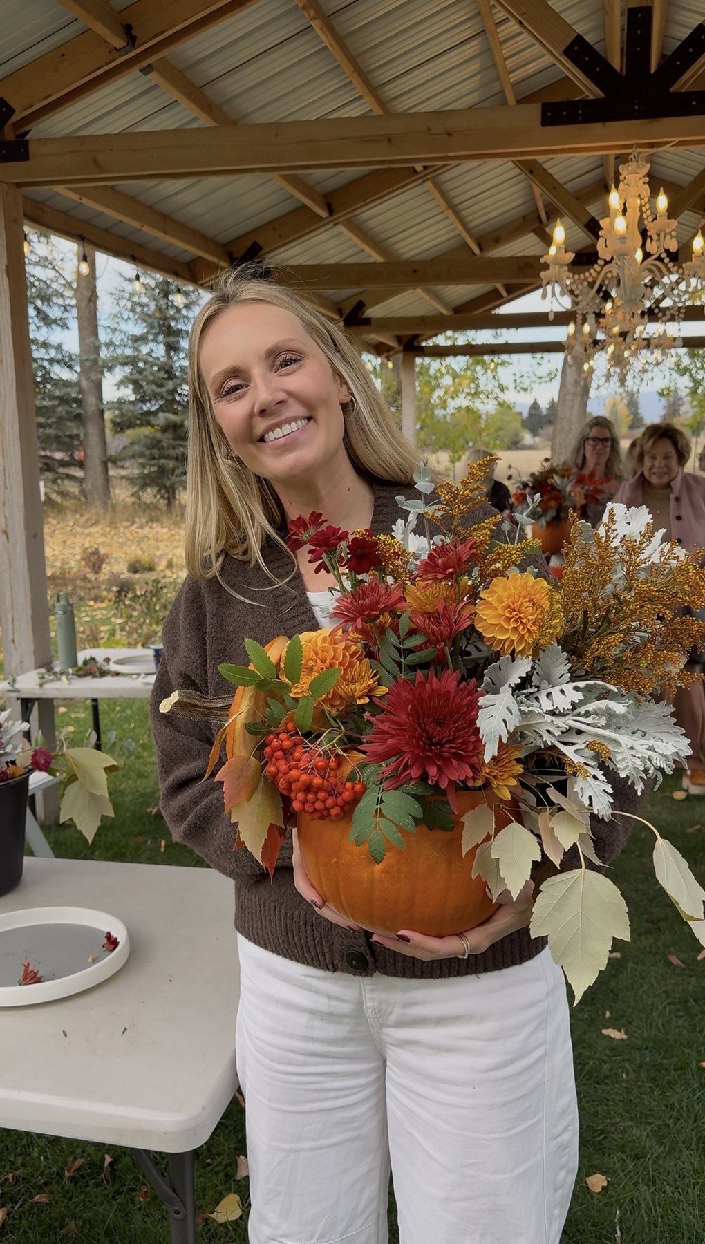 Kiana holding her finished pumpkin arrangement under the pavilion