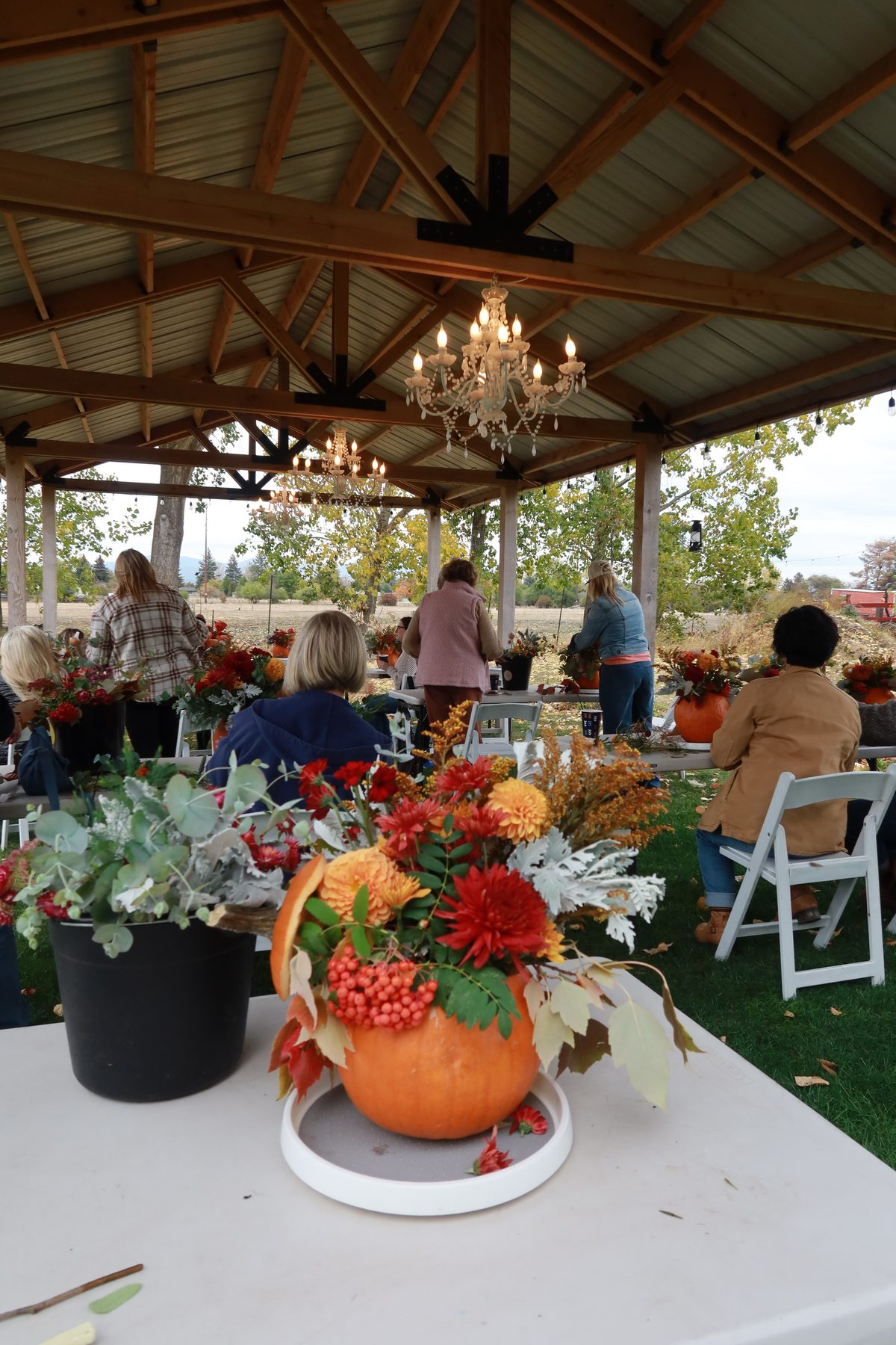 A finished pumpkin arrangement on the table under the chandelier-lit pavilion