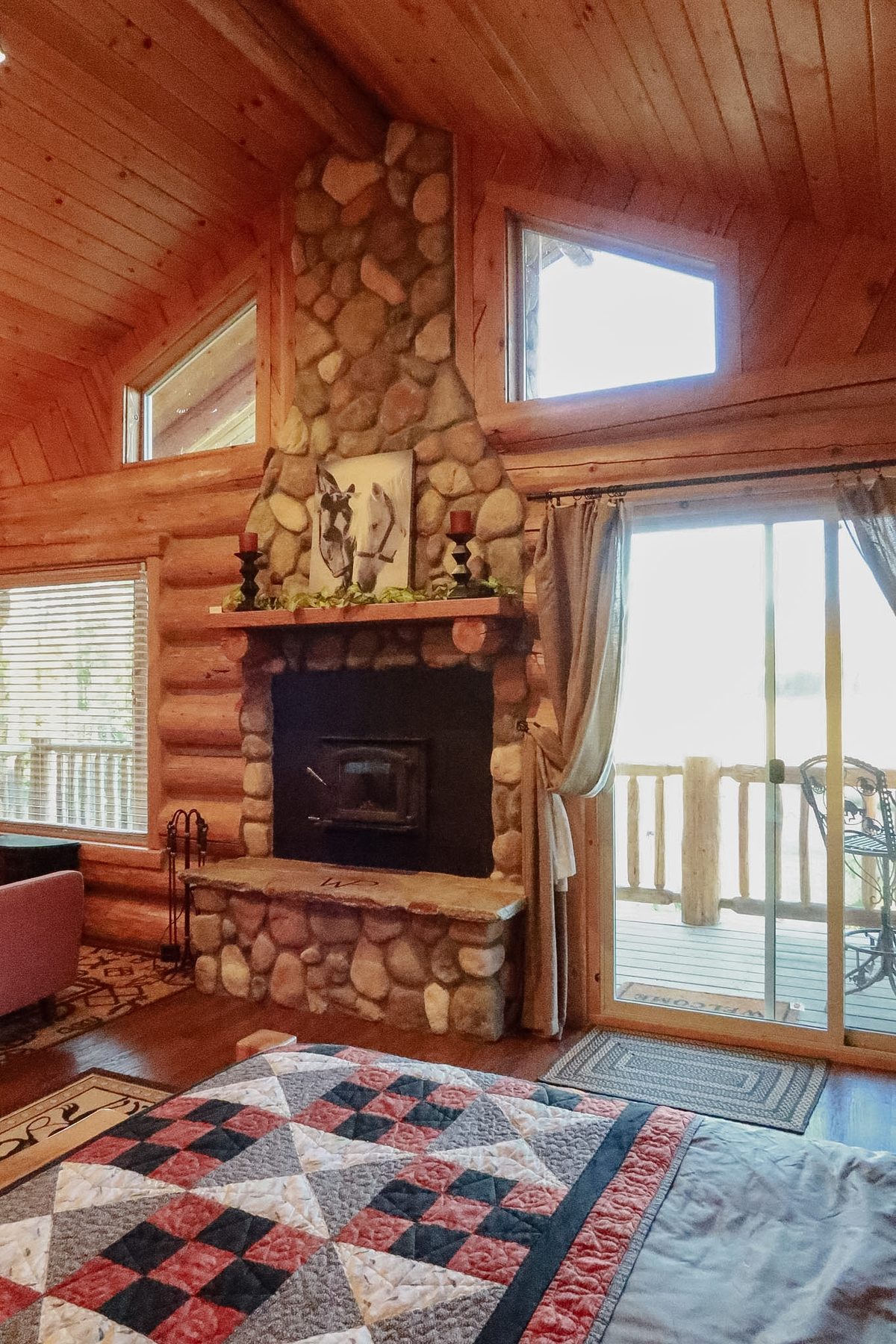 A guest room with a stone fireplace and quilt