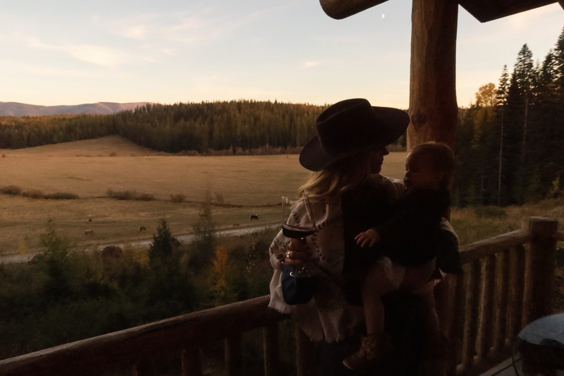 Silhouette of Kiana and our daughter on the lodge porch at sunset over the valley